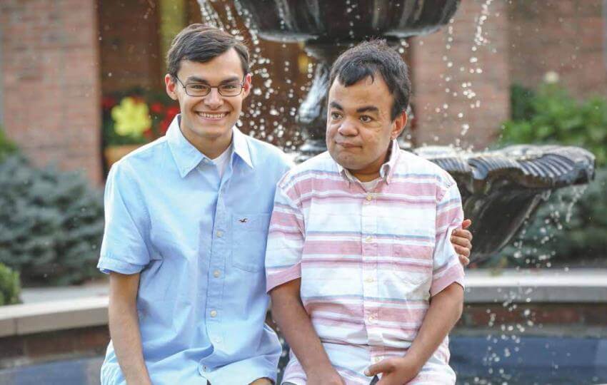 Twins Nathan and Nik Grant sit side by side near a fountain