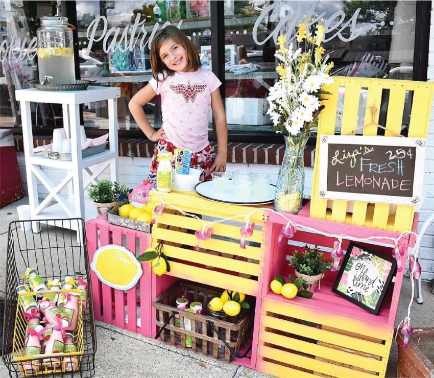 Liza Scott smiling next to her lemonade stand to help pay for her treatment