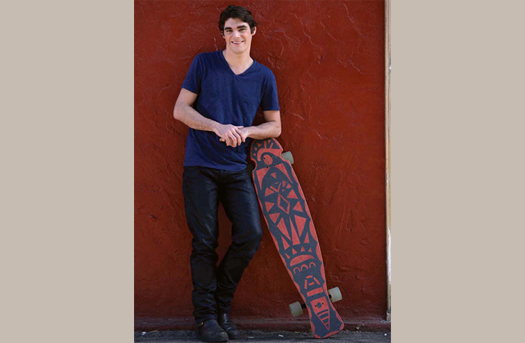 Actor RJ Mitte poses with a long board.