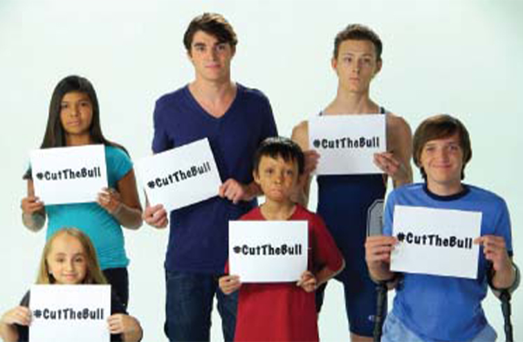 RJ Mitte and others holding signs that say "cut the bull" to raise awareness of bullying.