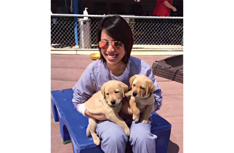 Christine Ha holding two future seeing eye dogs.