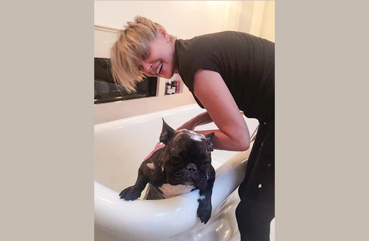 A smiling Sharon Stone photographed bathing her dog. 