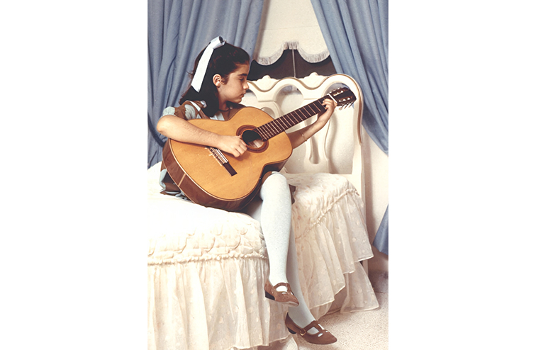 A young Gloria Estefan, playing guitar.