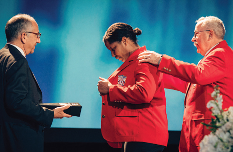 A red blazered Scurry on stage receiving her induction to the National Soccer Hall of Fame in 2017
