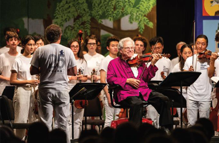 Itzhak Perlman on stage playing violin at Perlman School of Music in New York City.