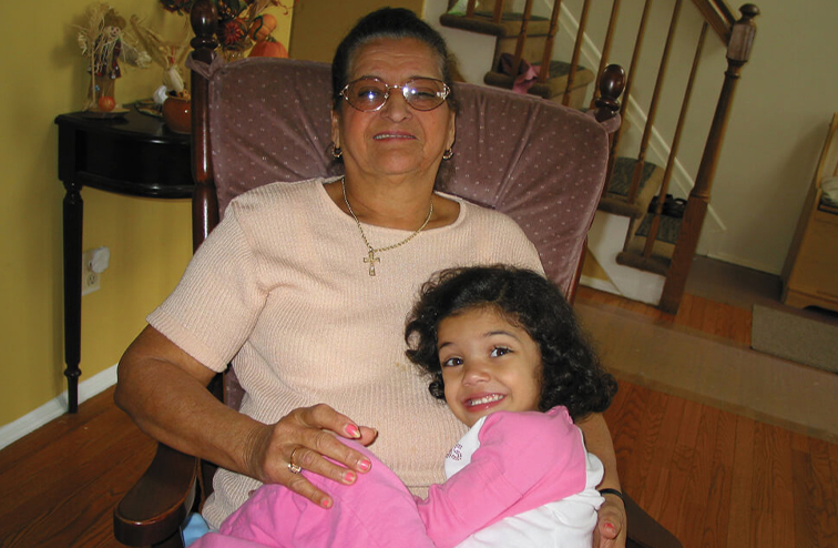 Laurie Hernandez as a child sitting with her grandma in a rocking chair.