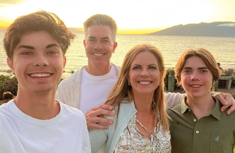 Morales with her husband, Joe Rhodes and their two sons pose for a picture in front of a sunset in Maui in 2022.