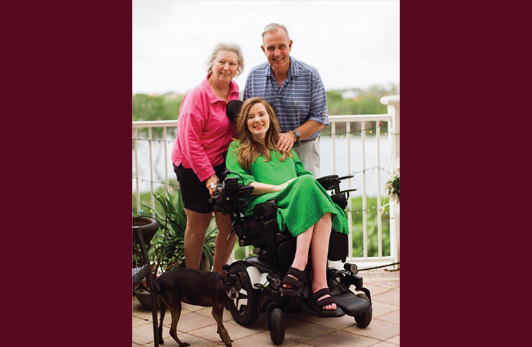 Brooke Eby wearing a green dress and sitting in her wheelchair next to her parents.