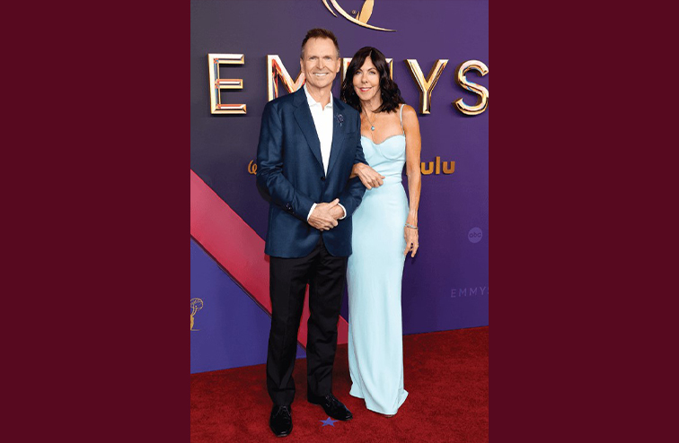 Phil, wearing a suit, and Louise Keoghan, wearing a floor length light blue gown, at the Primetime Emmy Awards in 2024 posing on the red carpet
